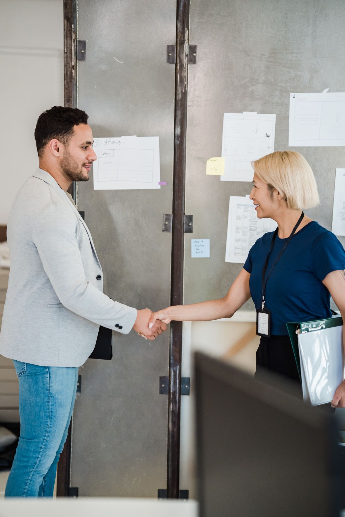 Twee professionals bezegelen een samenwerking met een handdruk in een moderne werkruimte