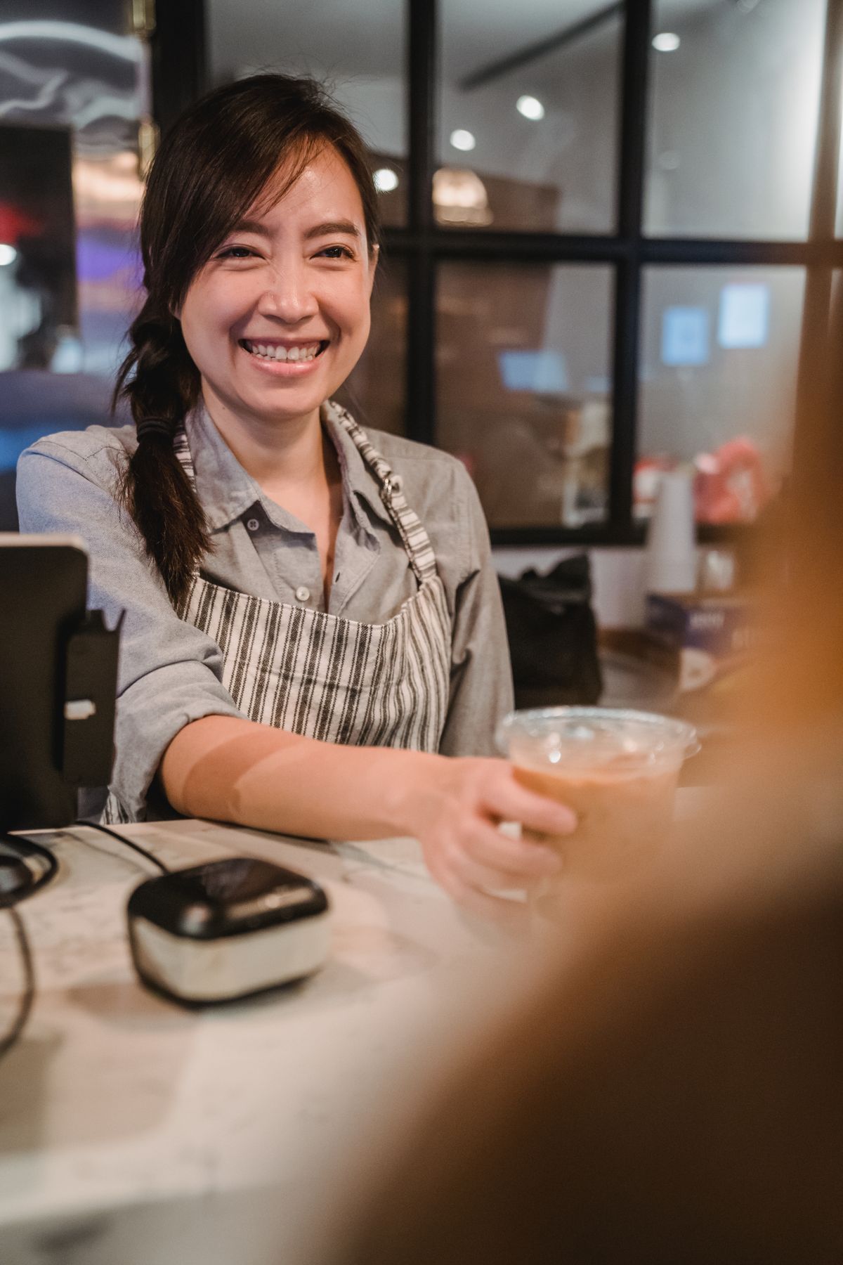 Lachende barista serveert een koffie aan de bar van haar koffiezaak