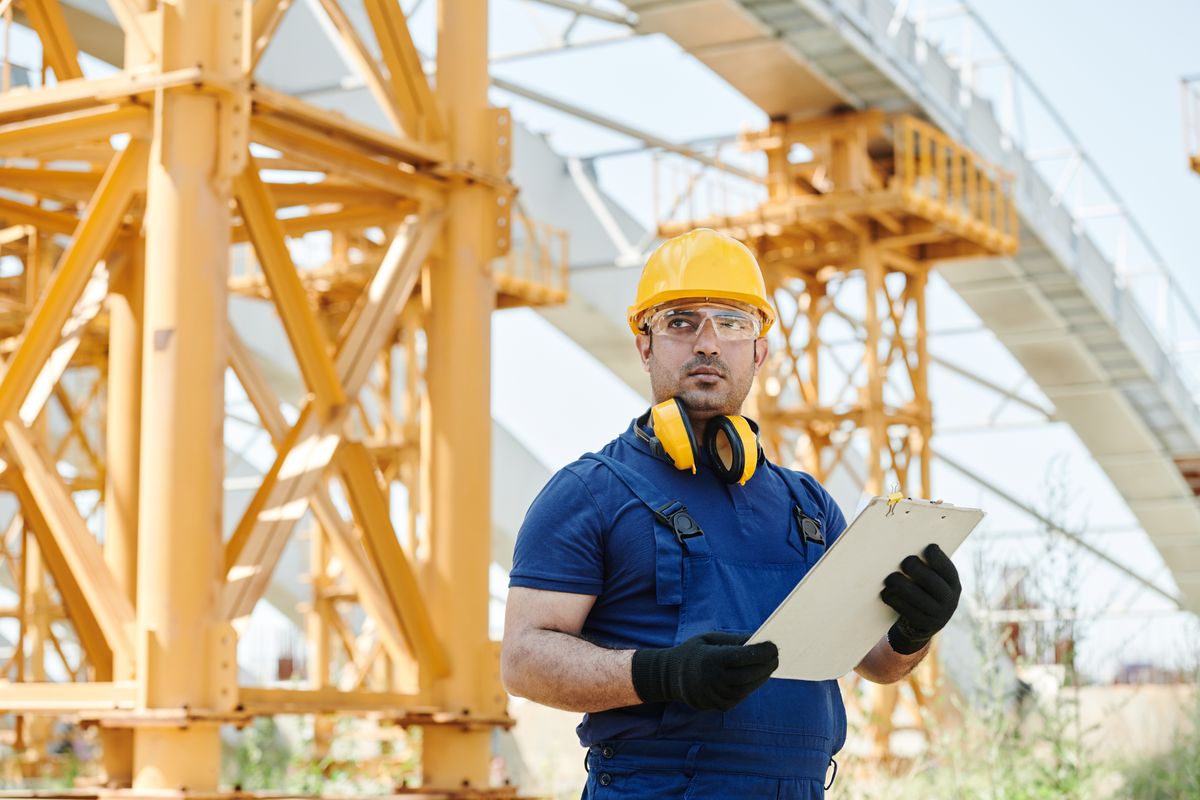 Medewerker met veiligheidshelm loopt met een checklist over de werklocatie